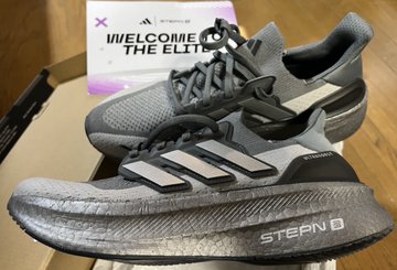 A pair of gray Adidas Ultraboost sneakers with the word 'STEARN' on the sole, displayed on a box that reads 'WELCOME THE ELITE'.