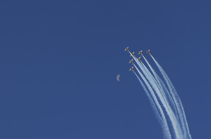A formation of jets ascends through a deep blue sky, leaving white contrails in their wake, with a faint crescent moon visible in the background. The image visually echoes the post's message about embracing the vastness of the sky and taking bold leaps, symbolizing freedom and the pursuit of something greater.