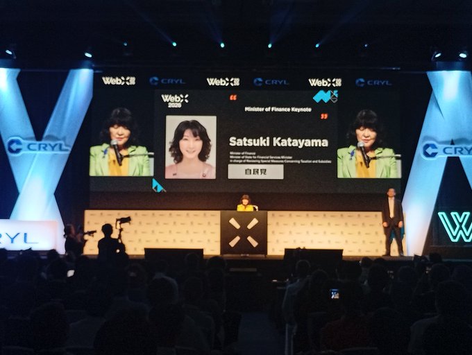 A WebX 2025 conference stage featuring a presentation about Satsuki Katayama, identified as Japan's Minister of Finance, with WebX and CRYL branding visible throughout the venue.