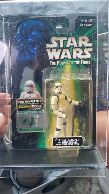 A vintage Star Wars 'The Power of the Force' Stormtrooper action figure in its original Kenner packaging with CommTech chip, displayed inside a protective plastic case.