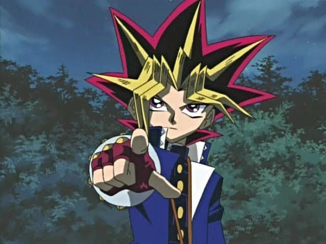 An anime character with spiky black, yellow, and magenta hair points a gloved fist toward the camera against a forested backdrop, evoking the iconic "Yami Yugi" pose from *Yu-Gi-Oh!* The defiant, confident gesture mirrors the post's frustration, symbolizing the poster's call for respect and pushback against dismissiveness surrounding the $Y2K token.