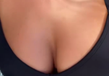 Close-up shot of a person's chest area, blurred and partially obscured, wearing a dark top.