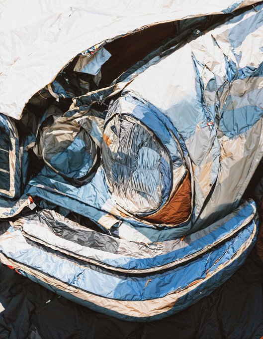 A close-up, stylized image showing a crumpled, reflective silver and blue fabric or inflatable material, possibly depicting a character like Stitch.