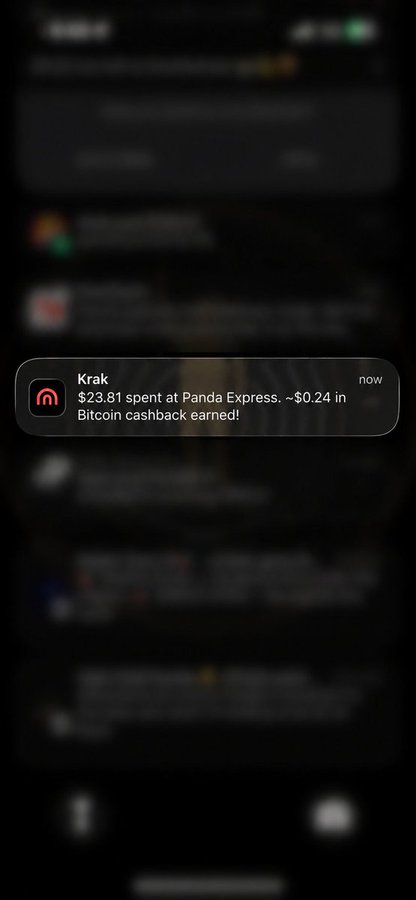 A smartphone notification from the Krak app reads: '$23.81 spent at Panda Express. ~$0.24 in Bitcoin cashback earned!' over a blurred background.