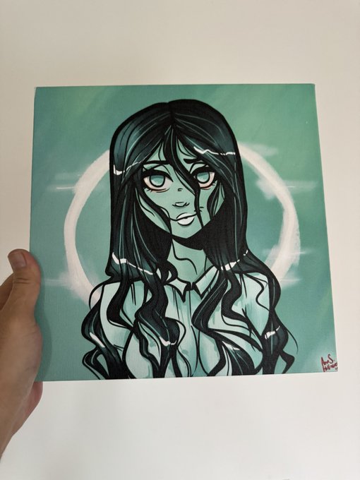 An anime-style drawing of a girl with long black hair and large eyes against a teal background with a white halo, held by a hand.