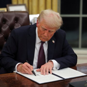 Former President Donald Trump is shown signing a document. This image is relevant to the post as it depicts a formal signing, potentially representing the execution of legislation or important policy, such as the CLARITY Act.