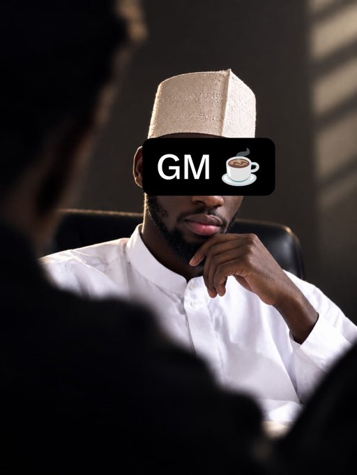 A man wearing a traditional cap and white thobe sits thoughtfully with his hand to his chin, while a 'GM' coffee cup emoji sticker obscures his eyes.