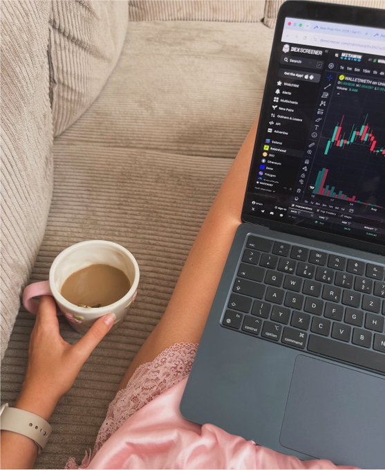 A first-person view of someone relaxing on a couch with a MacBook displaying the DexScreener app (showing 'SMALLETONETH') and a chart of $SMOL, while holding a mug of coffee or tea.