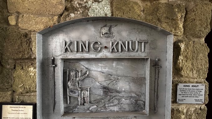 A stone monument titled 'KING KNUT' featuring a relief carving of a figure on a throne with a small ship above, alongside an informational plaque about King Knut's story of trying to hold back the tide.