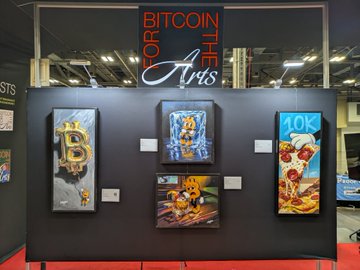 An art exhibition display titled 'BITCOIN FOR THE ARTS' featuring three Bitcoin-themed paintings mounted on a dark wall.