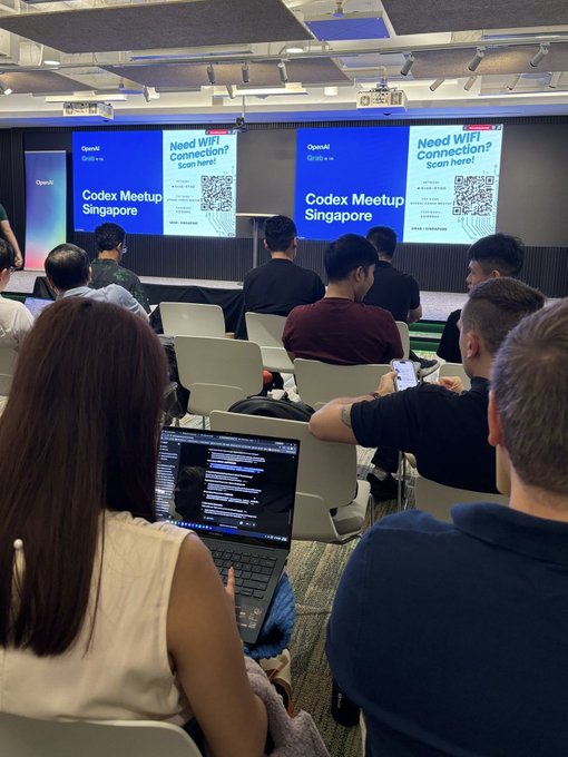 Attendees at a tech event sit facing large screens displaying 'Codex Meetup Singapore' and 'Need WiFi Connection? Scan here!' with a QR code.