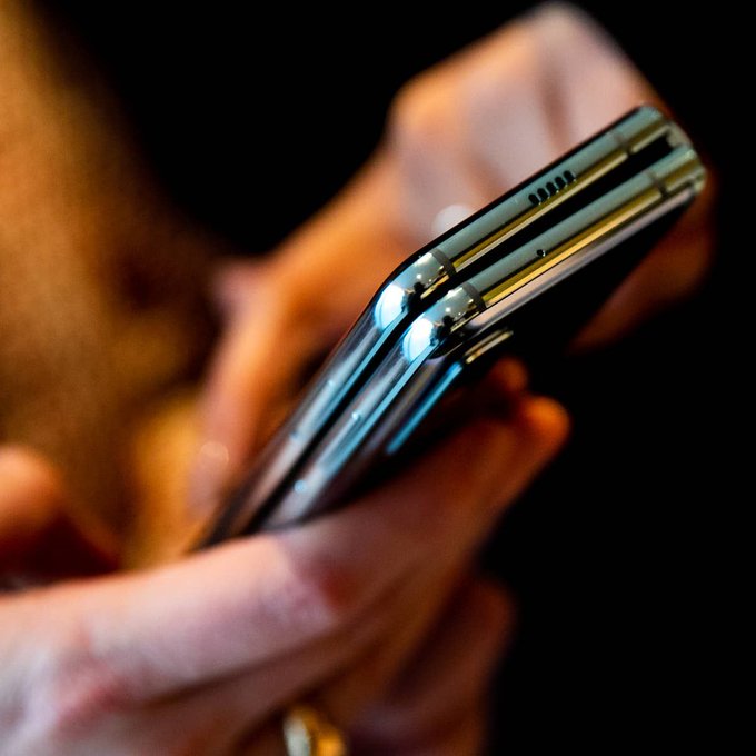 A close-up shows two Samsung phones stacked edge-to-edge, their slim profiles, speaker grilles, and reflective frames illuminated against a blurred hand, visually evoking the integration of Solana-based stablecoins across Samsung's vast mobile ecosystem.