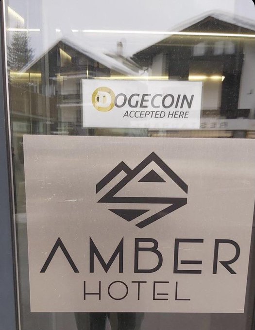 Glass doors display signs reading "AMBER HOTEL" and "DOGECOIN ACCEPTED HERE" with the Shiba Inu Doge logo.