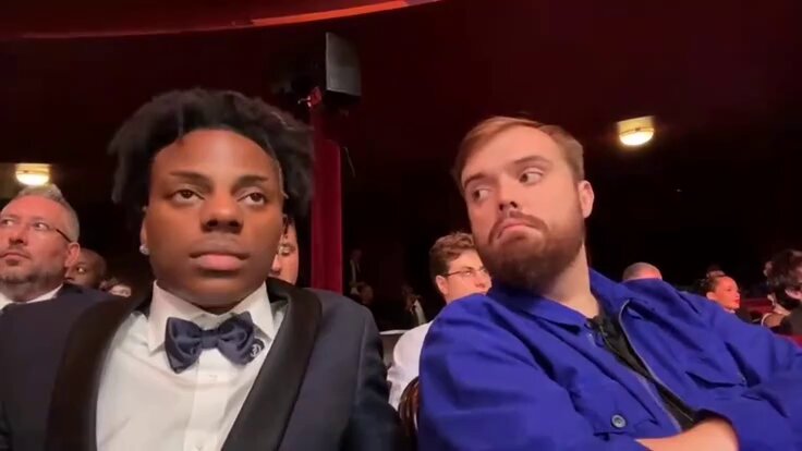 The image shows two men sitting next to each other, both wearing suits and ties. One man has a beard while the other has a mustache. They appear to be at an event or gathering, possibly watching a performance or presentation. The caption of the image reads " megaeth & monad all along".