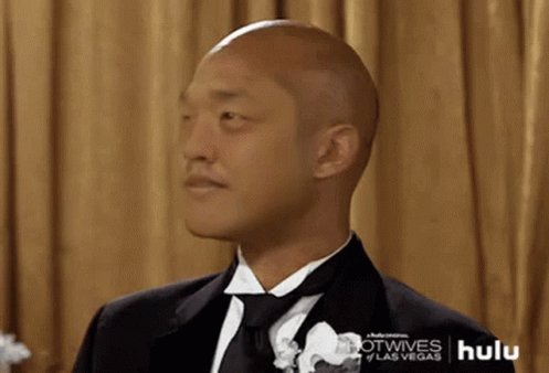 The image features a bald man wearing a suit, tie, and white flower boutonniere. He has a serious expression as he looks off into the distance with his head tilted back slightly. The caption of the image reads "Wow Do Kwon @stablekwon got out of prison early from the $luna collapse". This suggests that the man might be discussing or reacting to an event related to the post, possibly about the post's content or a story involving the character Kwon.