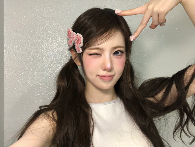A young woman with long dark hair styled in pigtails winks and flashes a peace sign, wearing a sparkly pink bow clip. The post's hashtag "#Sui Bubble" appears to reference the cute, bubbly aesthetic of her playful pose and pastel styling.
