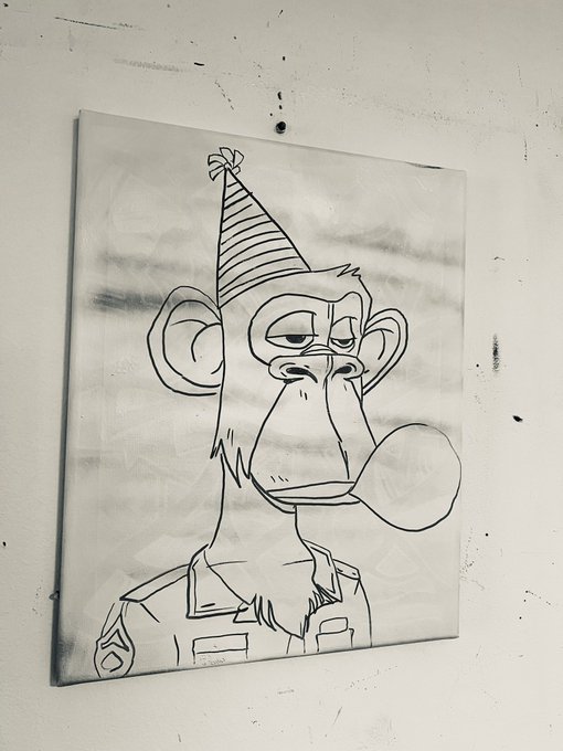 A canvas artwork mounted on a wall featuring a black and white line drawing of a bored-looking monkey wearing a striped party hat and overalls.