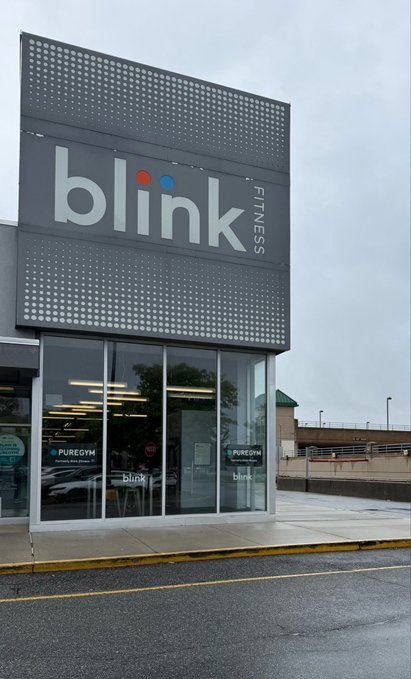 Exterior storefront sign for 'blink FITNESS' on a dark gray building facade.