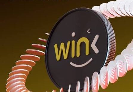 A 3D rendering of a black circular token or coin featuring a smiley face and the word 'wink' in yellow text, displayed against a dark background with stacks of coins.