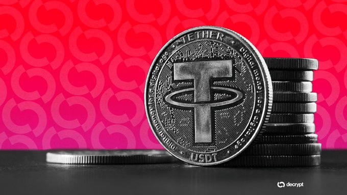 A close-up photograph of silver Tether ($USDT) coins stacked together with the prominent T logo, set against a pink background with repeating logo patterns, watermarked with 'decrypt'.