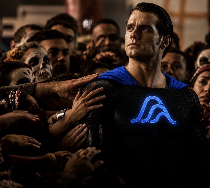The image shows Henry Cavill as Superman, with the iconic glowing blue "S" shield on his chest, surrounded by a crowd of people reaching toward him—including some with skull face paint in a Day of the Dead style. The post's message about original ideas being diluted by countless copies (using "Variational" and puns) pairs with the Superman imagery to suggest that true originality and strength—like Superman's unique "S" emblem—stands apart from imitations.