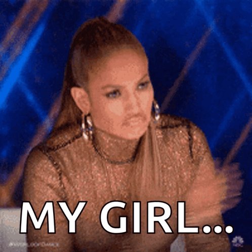The image features a woman with long brown hair wearing a sparkly top, sitting at a table or desk. She has her arms crossed over her chest and appears to be looking off into the distance. The caption of the image reads "My girl...grind never ends". This phrase is likely related to the ongoing COVID-19 pandemic, as it suggests that the woman's life may have been affected by the global crisis in some way or another.