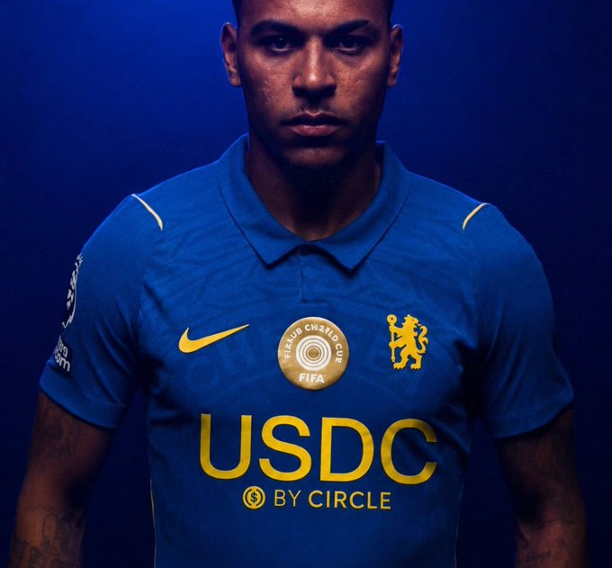 A male model, likely a football player, wears a blue Chelsea FC jersey prominently featuring the "USDC by Circle" sponsor logo alongside the FIFA Club World Cup emblem and Nike swoosh. The image illustrates the milestone of a major stablecoin brand becoming a main shirt sponsor for a Premier League club, visually reinforcing the post's message about crypto adoption entering mainstream visibility through everyday sports viewership.