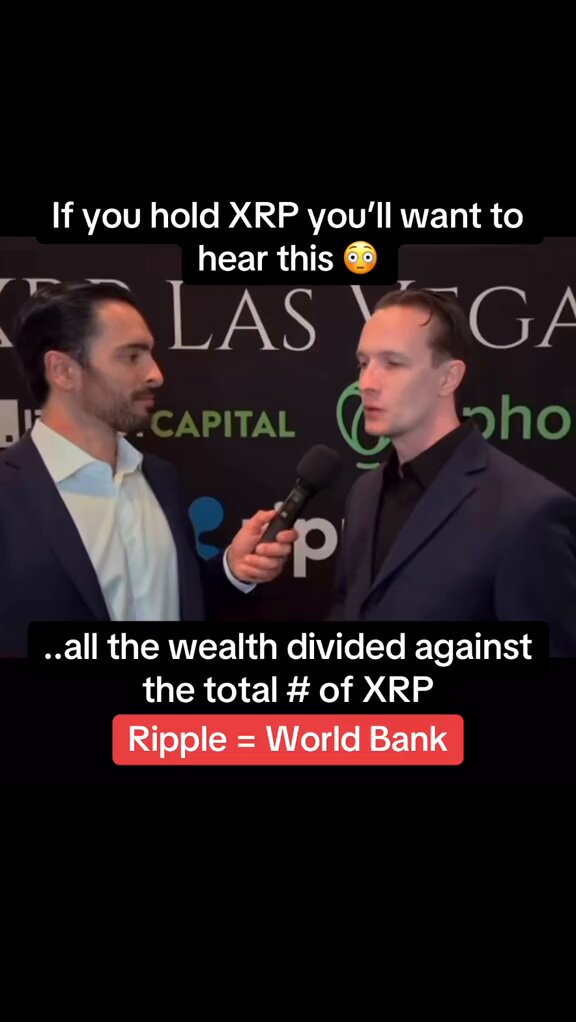 The image features a man wearing a suit talking into a microphone, with another man standing behind him. The background of the image shows a sign for Ripple cryptocurrency, which has been used as an example in the caption below the image.
