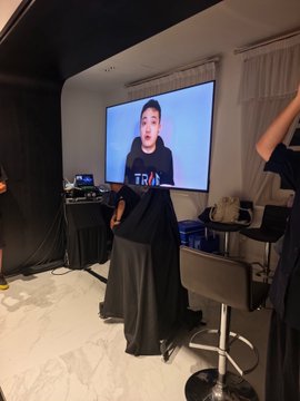 A woman stands in front of a large screen displaying a man wearing a "TRUMP" shirt, captured during the lively Huobi Future Night event where she is likely presenting insights about HTX holdings and the upcoming web3 wallet launch.