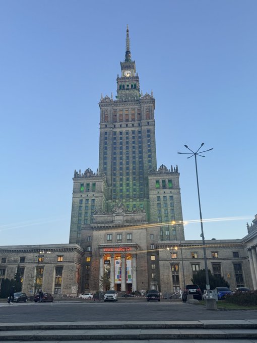 The Palace of Culture and Science (Pałac Kultury i Nauki) in Warsaw, a tall Stalinist-style building, is shown at dusk with a clear sky.