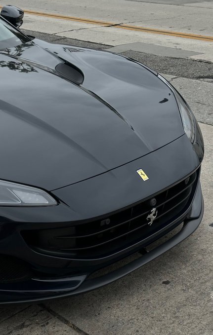 A close-up of a matte black Ferrari (badged with the iconic prancing horse logo on the front grille) parked on a street, fitting the post's caption about trading crypto for a luxury sports car.
