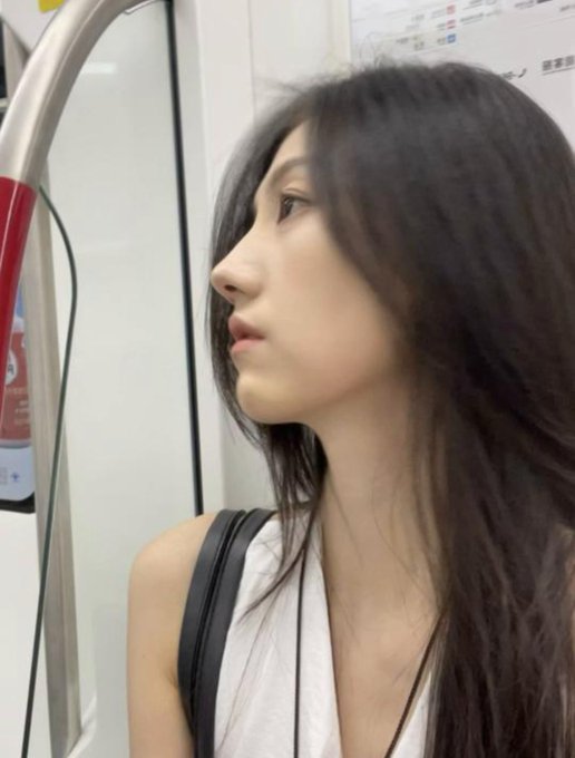 A young woman with long dark hair stands inside a subway car, gazing off to the side past a curved metal handrail. Her serene expression contrasts with the promotional caption encouraging users to register through a referral link to receive 500U in cash, framing her as an aspirational figure for potential crypto exchange sign-ups.