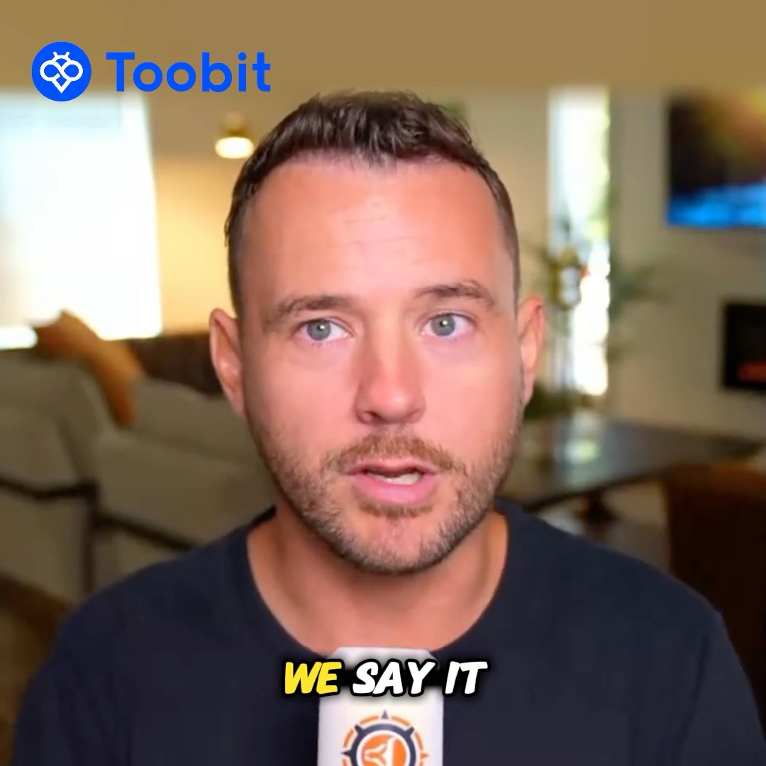 A man with short brown hair and stubble speaks directly to the camera in a blurred indoor setting, with the "Toobit" logo displayed in the top left corner and the yellow text "WE SAY IT" overlaid at the bottom. The image relates to the post as a still from a crypto commentary clip featuring Toobit partner DiscoverCrypto discussing market timing and accumulation strategies.