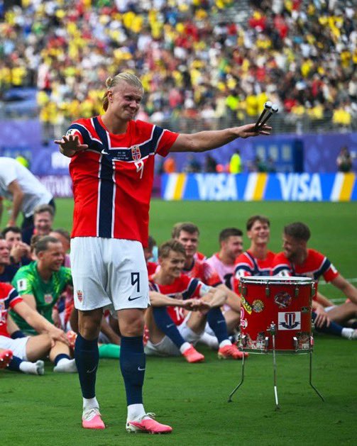 A Norwegian soccer player wearing jersey number 9 stands triumphantly on the field with arms outstretched, surrounded by seated teammates and a large crowd, with "VISA" branding visible on the stadium backdrop. The image captures a celebratory moment for Norway's national team, directly tying to the post's bet about Norway winning the World Cup.