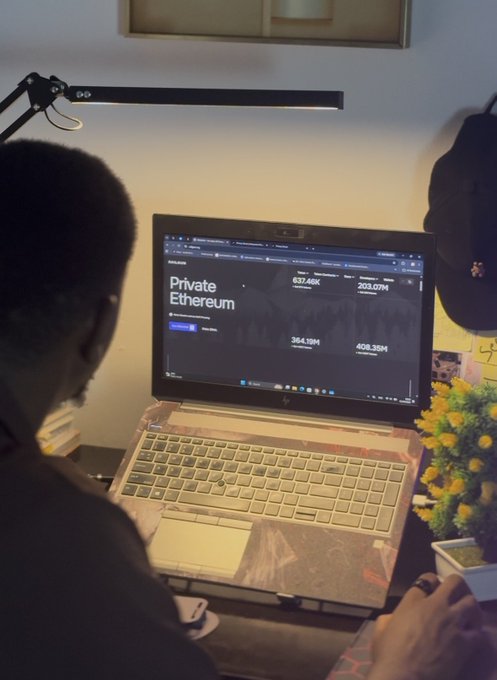 A person viewed from behind looks at an HP laptop screen displaying a website about "Private Ethereum" with various numerical statistics.