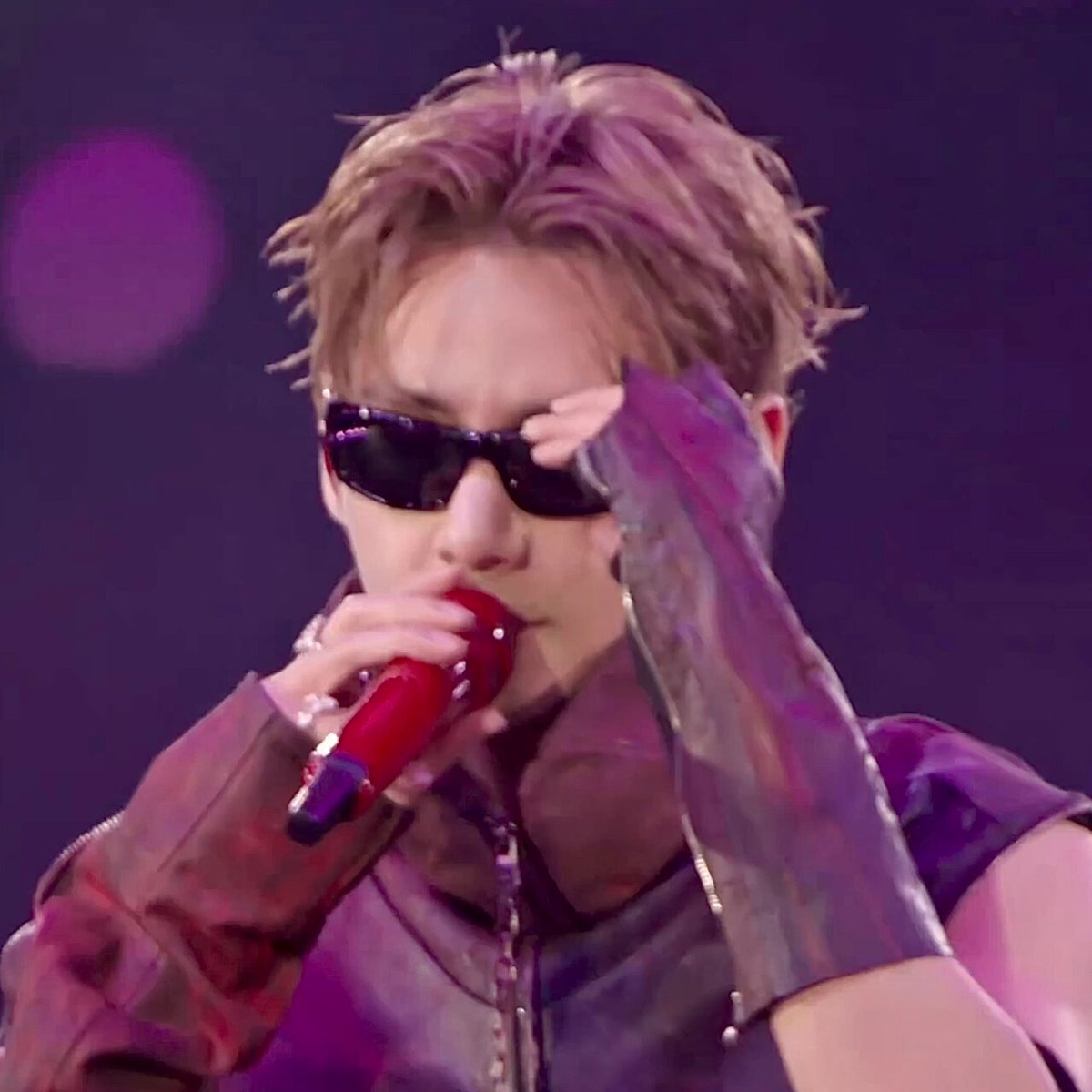 The image features a young man wearing sunglasses, a leather jacket, and gloves while singing into a microphone. He appears to be performing at an event or concert. The caption "AURA FARMING FINAL BOSS" suggests that this could be related to a performance by the singer named Aura Farming, who is known for her powerful voice and stage presence.