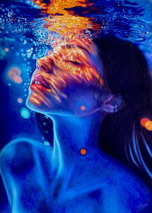 A vivid underwater portrait shows a submerged woman with eyes closed as warm orange light patterns ripple across her face against a deep blue background.
