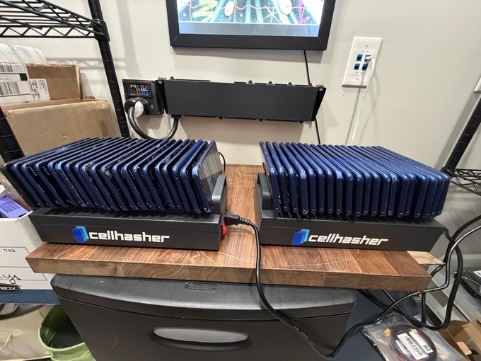 Two Cellhash mining devices with stacks of blue cell phones are set up on a wooden board in what appears to be a cryptocurrency mining operation.