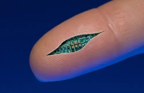 A close-up shows a tiny electronic chip embedded in the fingerprint pattern of a human fingertip against a blue background.