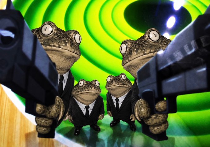 Four suited amphibian figurines point large guns directly at the camera against a green spiral background, evoking a tense standoff that humorously parallels the meme's alarm over a small $FRONG sell-off.