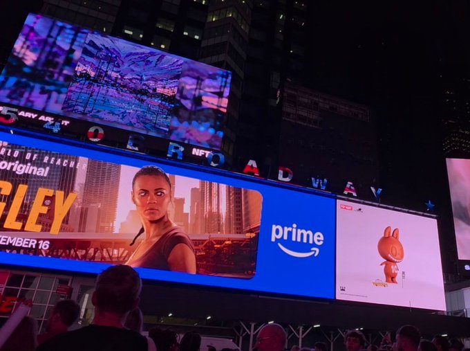 A nighttime view of Times Square billboards featuring advertisements including Amazon Prime and what appears to be a Peacock promo.