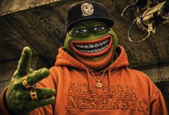 Grinning green character wearing an orange hoodie and a black cap with a skull logo.