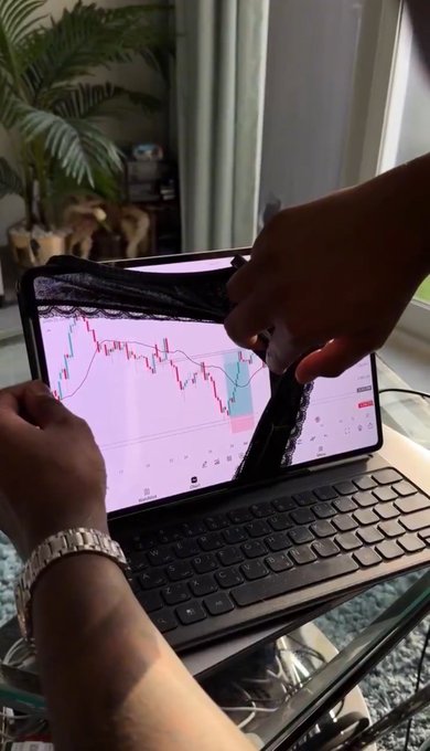 A person's hands are shown placing a black plastic cover over a tablet displaying a financial trading chart, resting on a keyboard.