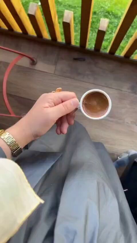 The image features a person holding a cup of coffee, with their hand positioned over the cup as if they are about to take a sip. The background shows a wooden fence or railing, suggesting that this scene takes place outdoors. There is also an element of text in the image, which reads "Good morning everyone My favorite projects lately and why I'm creating content for them @TheARCTERMINAL They don't just leave AI in the realm of theory they turn it into tools that people can actually use".