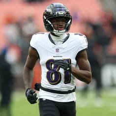 A Baltimore Ravens football player wearing jersey number 87 runs on the field in a white away uniform with purple lettering.