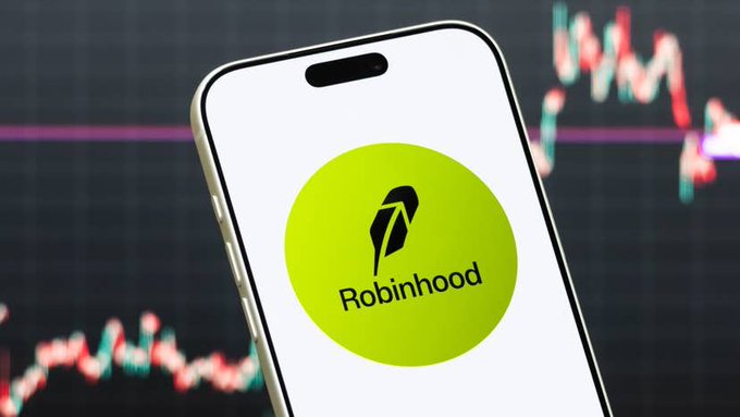 A smartphone showing the Robinhood logo in the foreground, with a blurred stock market chart in the background displaying candlestick patterns, illustrating the article about an analyst's stock picks for the Roundtable 100.