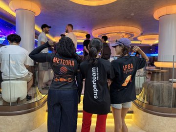 Three members of the Superteam Thailand community, wearing branded black shirts with "Meteora," "superteam," and "LPSA" logos, stand together with arms around each other at a co-working space event. The image captures the casual, collaborative atmosphere described in the post, where Solana builders—including representatives from projects like Meteora, Jupiter, and LPSA—gathered to connect beyond just the 40+ person headcount.