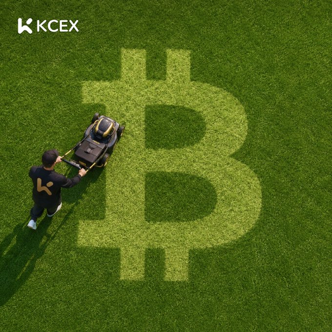 An aerial view of a person pushing a lawnmower over grass that has a large Bitcoin '₿' symbol cut into it, with the KCEX logo in the corner.