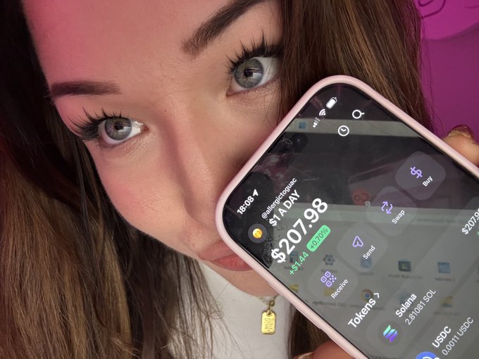 A close-up of a woman with blue eyes holding a phone showing her crypto portfolio valued at $207.98 (+0.70%), featuring tokens like Solana and USDC.