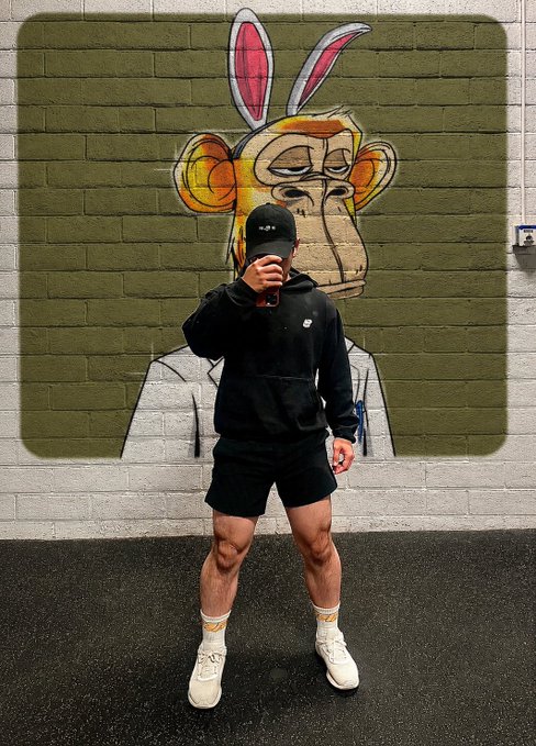 iced coffee cup with "M" and "C" logo, accompanied by a black hat and white sneakers, against a green brick wall backdrop.
